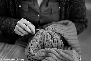Eine Mitarbeiterin von Fisherman out of Ireland nimmt Ausbesserungsarbeiten an einem Kleidungsstück vor.