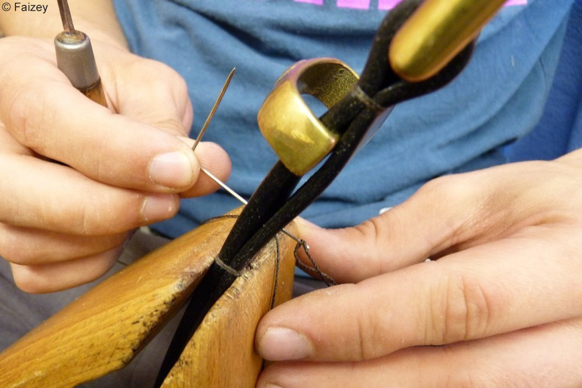 An einem Ledergürtel von Faizey Leather Goods wird von Hand genäht.