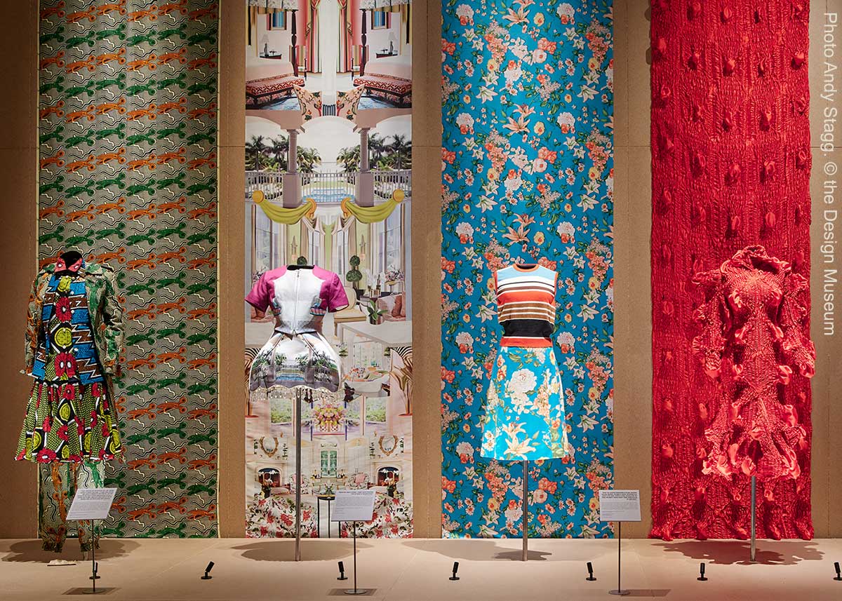 Vier Kleider im Ausstellungsraum "Colour Explosion" der Ausstellung "REBEL: 30 Years of London Fashion"